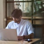 Man at a laptop checking whether a domain name is available for his UAE business
