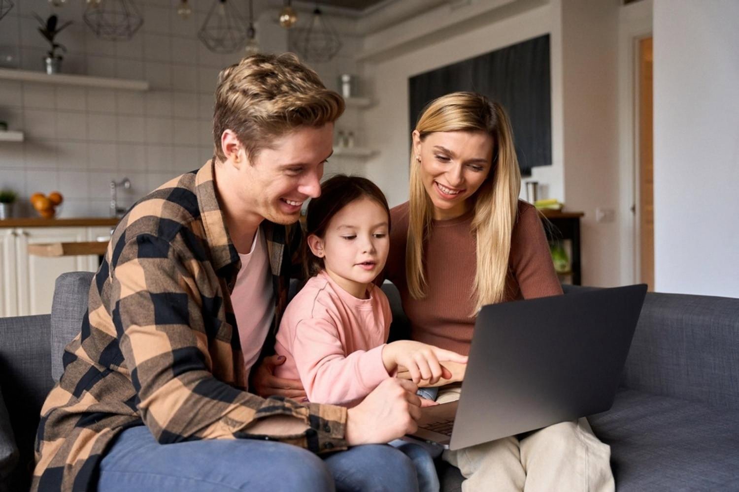 Family sitting on a sofa browsing domain registration options on a laptop